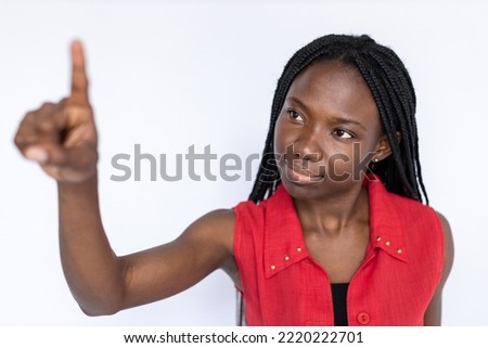 Interested woman touching virtual screen. Female African American model in red vest scrolling virtual screen, pressing bottoms. Portrait, studio shot, technology concept