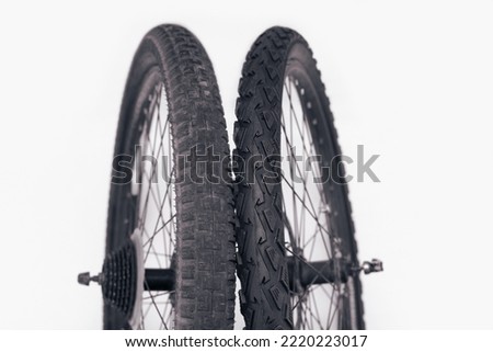 Old and new bicycle tires, comparison of an old tire with worn spikes and a new bicycle tire, the concept of timely replacement of tires for transport, close up Royalty-Free Stock Photo #2220223017