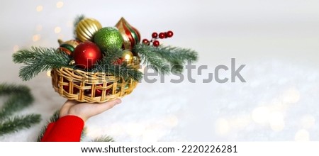 Young pretty woman with red knitted sweater holding in her hand basket of christmas toys. Сhristmas and new year concept. close up  hands  with basket christmas toys. Greeting card. banner