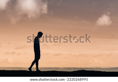 Man with head down walking alone outdoors silhouette 