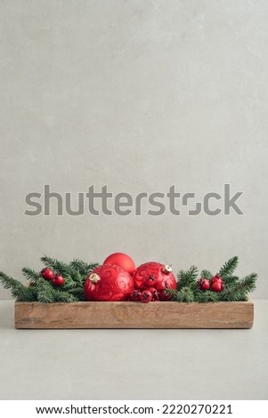 Christmas decorations from fir tree branches and red christmas balls in wooden box on light background