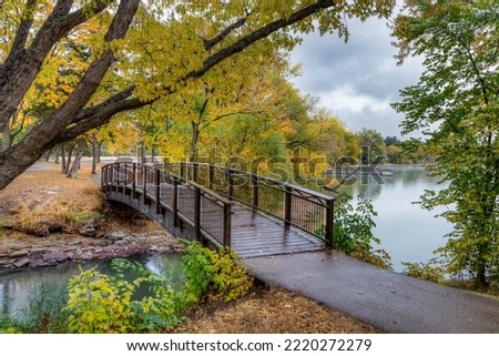 Walking bridge in autumn over Lake Nokomis in Minneapolis, Minnesota. Royalty-Free Stock Photo #2220272279