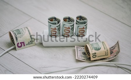 Us dollars banknotes into electrical outlet and next to cord. Home financial budget concept.