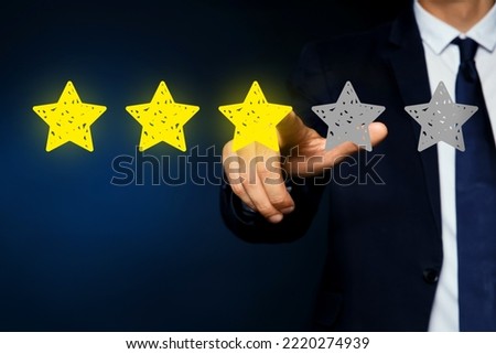 Man pointing at icons of stars on dark blue background, closeup. Quality rating