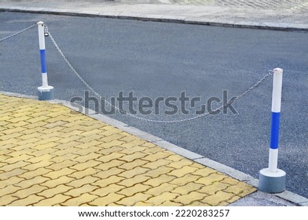 Chain barrier stands near asphalt on autumn day