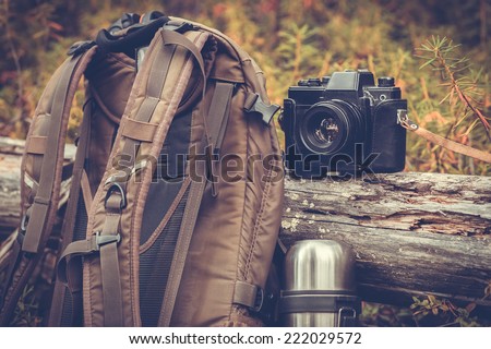 Lifestyle hiking camping equipment retro photo camera backpack and thermos outdoor forest nature on background
