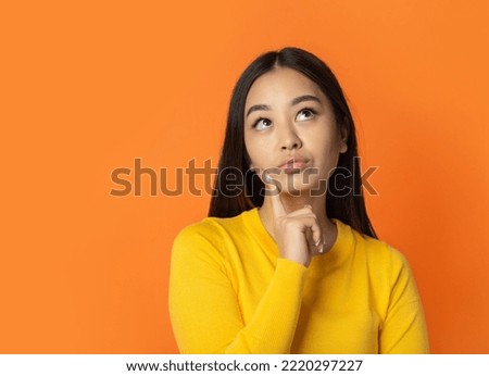Beautiful young thinking woman thoughtful on orange background with copy space