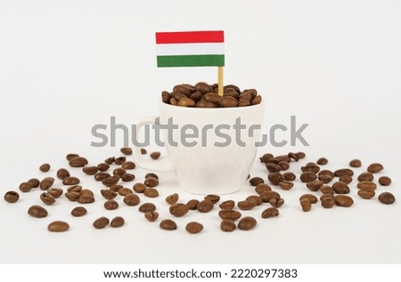 The flag of Hungary sticks out of a cup of roasted coffee beans. Concept of consumption and business.