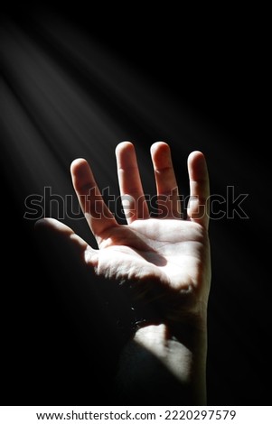 man hand up gesturing in the shadows, dark background