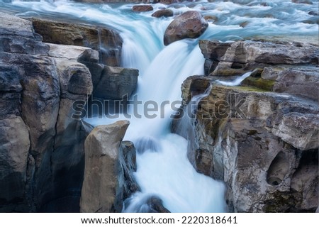 Waterfall and rocks. Long exposure photography. Fast river and waterfall. Natural background and wallpaper. Blurry fast water.