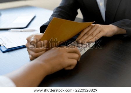 Asian businesswoman taking bribes to nonviolent officials Sign a business project contract put money under the envelope Corruption and anti-bribery concept.