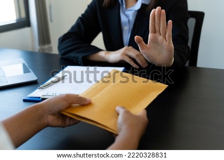 Anti-Bribery and Corruption Concept Asian businesswoman refuses and does not receive banknotes in brown envelopes, and offers from businessmen to accept investment agreements. Royalty-Free Stock Photo #2220328831
