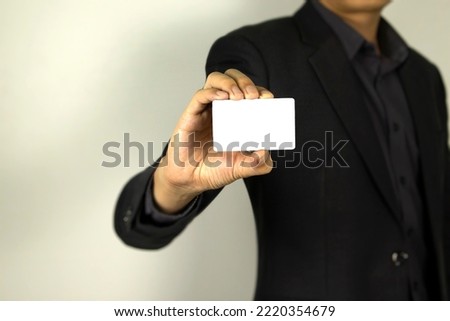 Business Man wearing smart suit and holding whit ID card in his hand, A smart man holding white mock up card, used in card design poster. Royalty-Free Stock Photo #2220354679