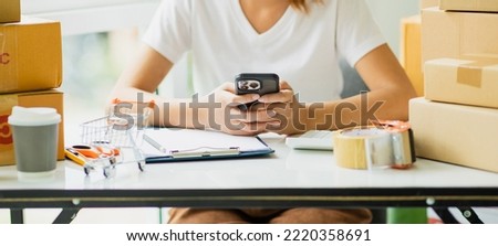 Starting a small business SME Close-up picture of entrepreneurs of an independent Asian woman using a smart phone with box cheerful success Her Asian woman raises her hand for online marketing packagi