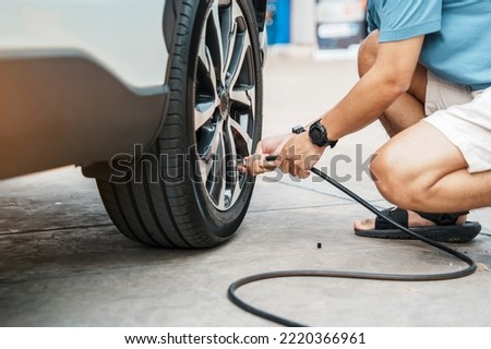 man driver hand inflating tires of vehicle, removing tire valve nitrogen cap for checking air pressure and filling air on car wheel at gas station. self service, maintenance and safety Royalty-Free Stock Photo #2220366961