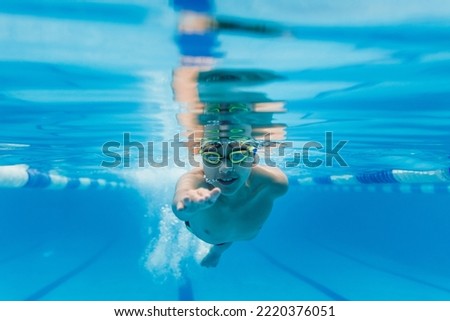 latin child boy swimmer wearing cap and goggles in a swimming underwater training In the Pool in Mexico Latin America Royalty-Free Stock Photo #2220376051
