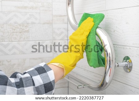 cleaning service. bathroom cleaning and disinfection. hand in yellow rubber glove wipes chrome heated towel rail in bathroom