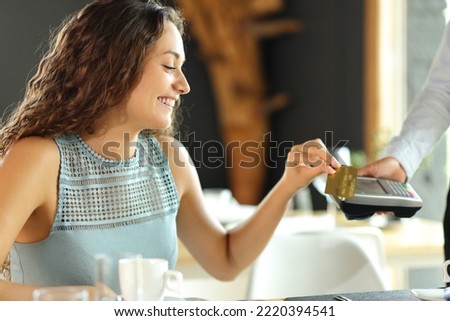 Happy customer in a restaurant paying with credit card Royalty-Free Stock Photo #2220394541