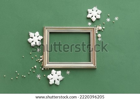 Composition with empty picture frame and Christmas decorations on green background