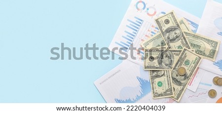 Dollar banknotes with coins and diagrams on blue background with space for text. Exchange rate concept