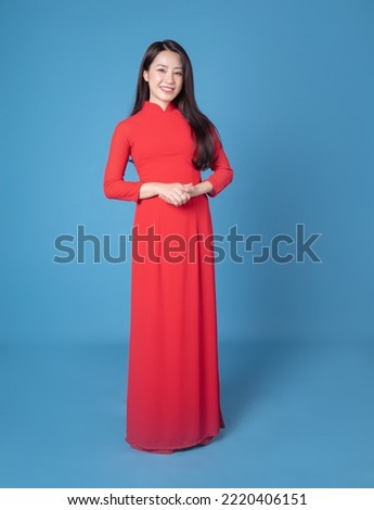 Full length image of young Vietnamese woman wearing red ao dai on background Royalty-Free Stock Photo #2220406151