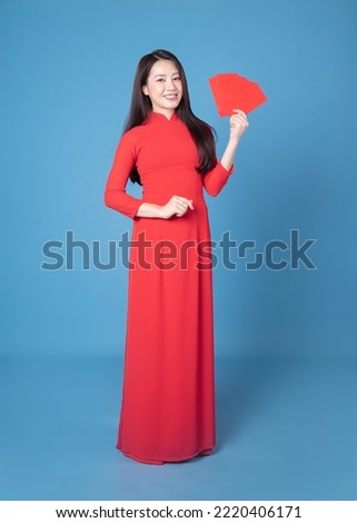 Full length image of young Vietnamese woman wearing red ao dai on background Royalty-Free Stock Photo #2220406171