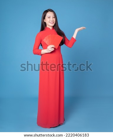 Full length image of young Vietnamese woman wearing red ao dai on background Royalty-Free Stock Photo #2220406183