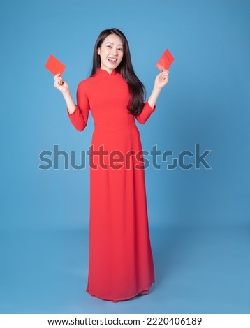 Full length image of young Vietnamese woman wearing red ao dai on background Royalty-Free Stock Photo #2220406189