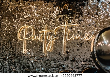 Silver photo booth with decor shiny and led strips with text party time. Zone with sparkling sequins. Glittery festive wall for wedding. A place for congratulations on birthday. Happy New Year 2023.