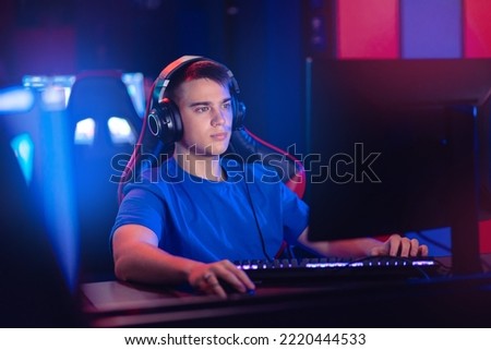 Young caucasian man pro gamer streamer playing in online video game, neon color soft focus.