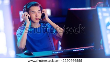 Happy Young asian man pro gamer streamer playing in online video game, neon color soft focus. Concept banner cyber esport Korean.