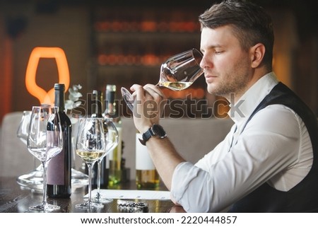 Wine expert smells alcoholic drink to give it rating. Royalty-Free Stock Photo #2220444857