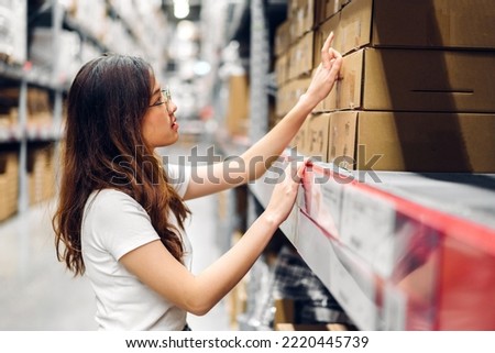 Portrait asian engineer woman shipping order detail check goods and supplies on shelves with goods background inventory in factory warehouse.logistic industry and business export