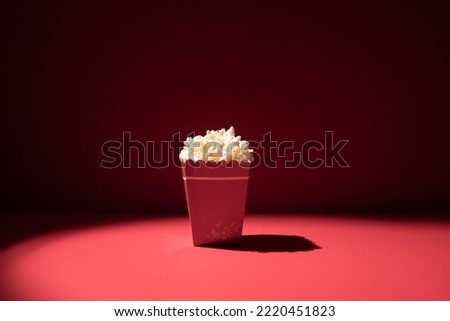 Box full of popcorn on red background. Cinema concept