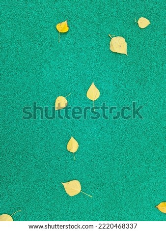 Green background with yellow autumn leaves. Green gravel. Autumn weather, brighter days. Suitable for postcards, promotions, websites, printing, social networks.