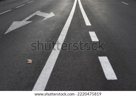 Photography with direction lines on a dark gray asphalt. White lines painted on the road.