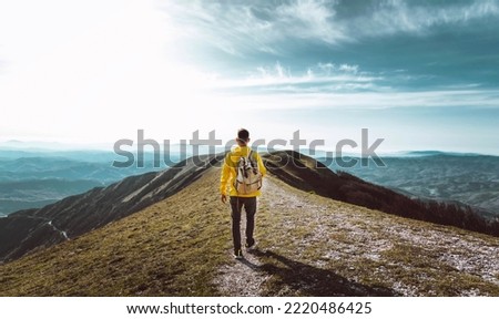 Young man with backpack hiking mountains - Hiker having trekking day out on a sunny day - Successful, sport and inspirational concept Royalty-Free Stock Photo #2220486425