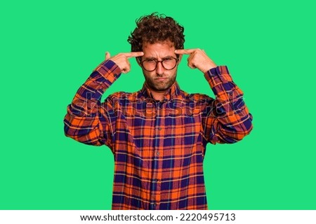 Young caucasian curly hair man isolated Young caucasian man with curly hair isolated focused on a task, keeping forefingers pointing head.
