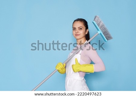 woman in gloves and cleaner apron holding broom