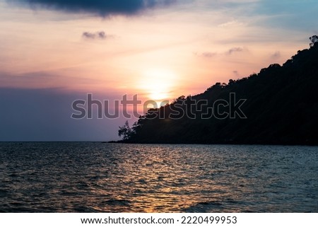 Silhouette of rock during sunset and waves at a beach in Kota Kinabalu, Sabah, Borneo with long exposure effect of sky and ground