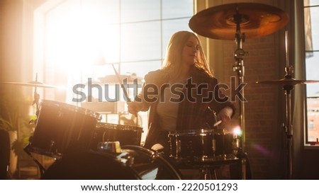 Expressive Drummer Girl Playing Drums in a Loft Music Rehearsal Studio Filled with Light. Rock Band Music Artist Learning Drum Solo. Portrait of Woman Enjoying Creating Rythm. Royalty-Free Stock Photo #2220501293