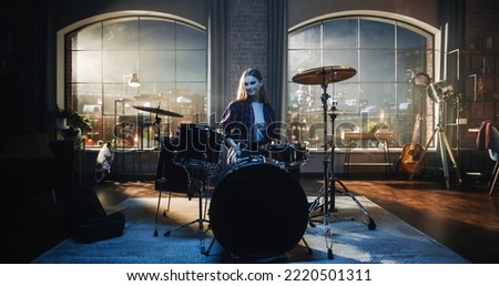 Expressive Drummer Girl Playing Drums in a Loft Music Rehearsal Studio at Night. Rock Band Music Artist Learning a New Drum Solo Before Upcoming Live Music Show on Big Stage. Royalty-Free Stock Photo #2220501311