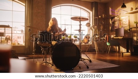 Female Drummer with Long Hair, Nose Piercing and Strong Make-up, Dressed in Dark Jeans and Checkered Flannel Shirt, Playing Drums in a Loft Studio Apartment. Preparing for Live Concert on a Big Stage. Royalty-Free Stock Photo #2220501403