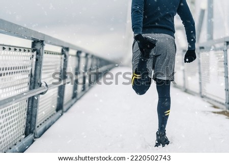 Handsome middle age man with a beard running and exercising outside on extremely cold and snowy day. Sport and fitness motivation theme. Royalty-Free Stock Photo #2220502743