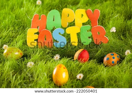 Happy Easter colorful wooden letters and easter eggs on a fresh grass.