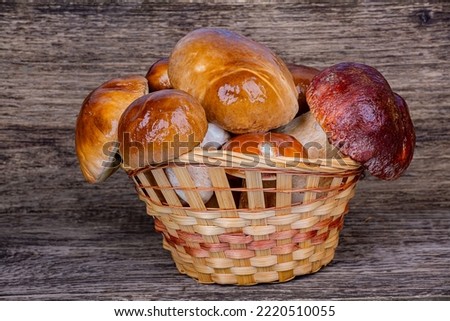Full wicker basket of porcini mushrooms on a wooden background, close-up
