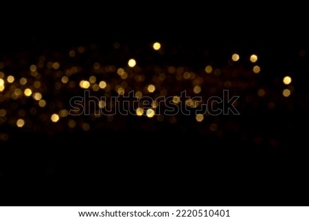 Golden blurred bokeh lights on black background. Glitter sparkle stars for celebrate. Overlay for your design Royalty-Free Stock Photo #2220510401