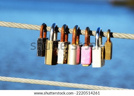 Old, rusty padlocks hang on a metal wire on a blue background.  A sign of strong love.