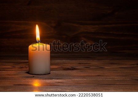 one burning candle on wooden background in minimalist room interior, copy space