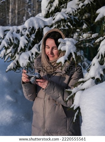 Young woman photographing winter forest using old vintage camera